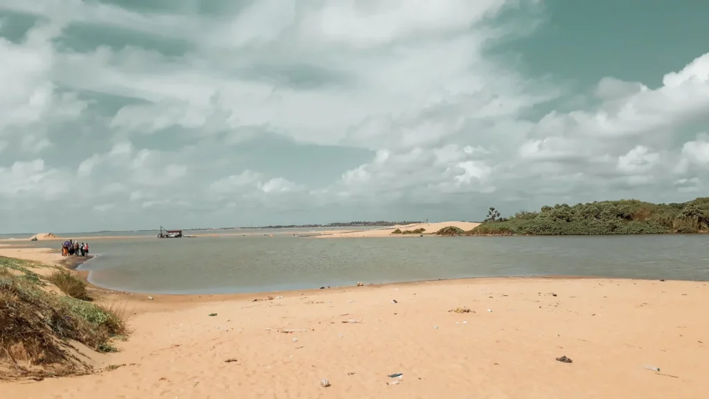Sandy estuary shore and low sand spits beside calm water under cloud at Chilaw, Sri Lanka
