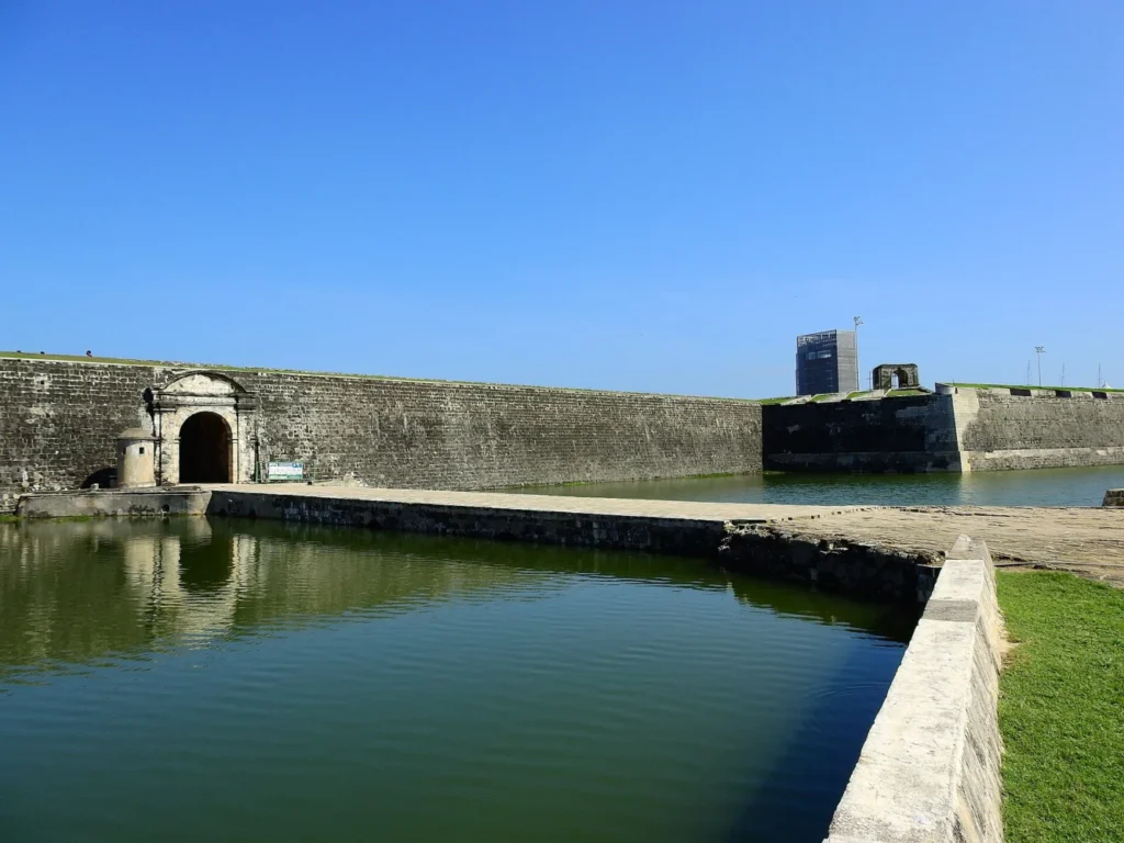Stone walls and an arched gateway reflected in the moat at Jaffna Fort, Sri Lanka