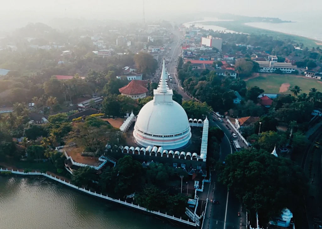 Aerial view of the white Kalutara stupa beside the river, with the surrounding town in haze, Sri Lanka