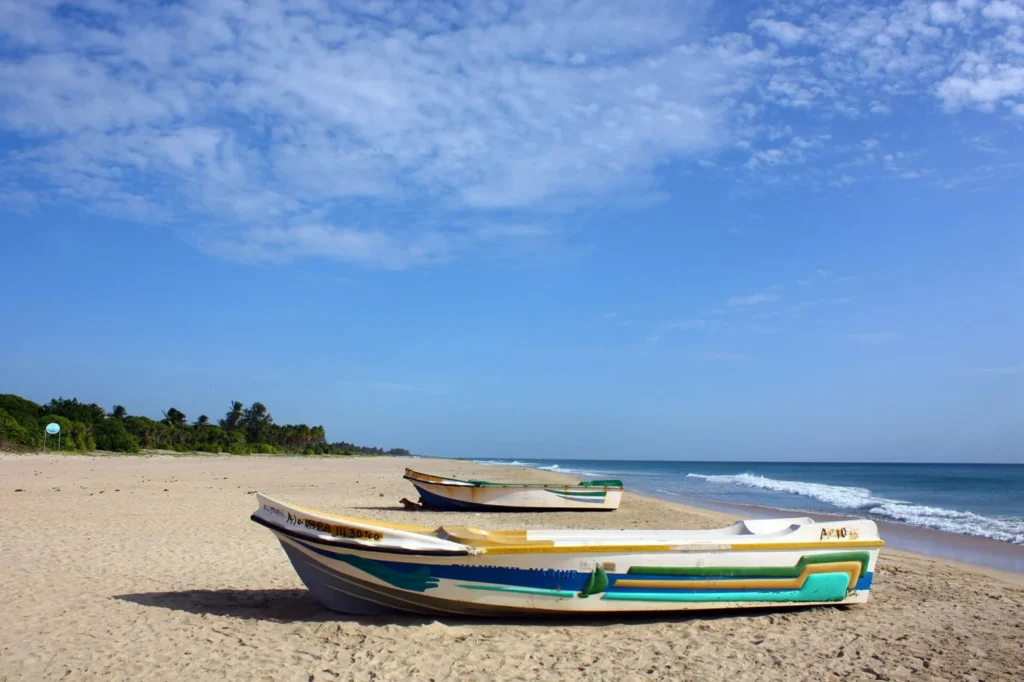 Small colourful fishing boats resting on the sand beside the sea at Nilaveli Beach, Sri Lanka