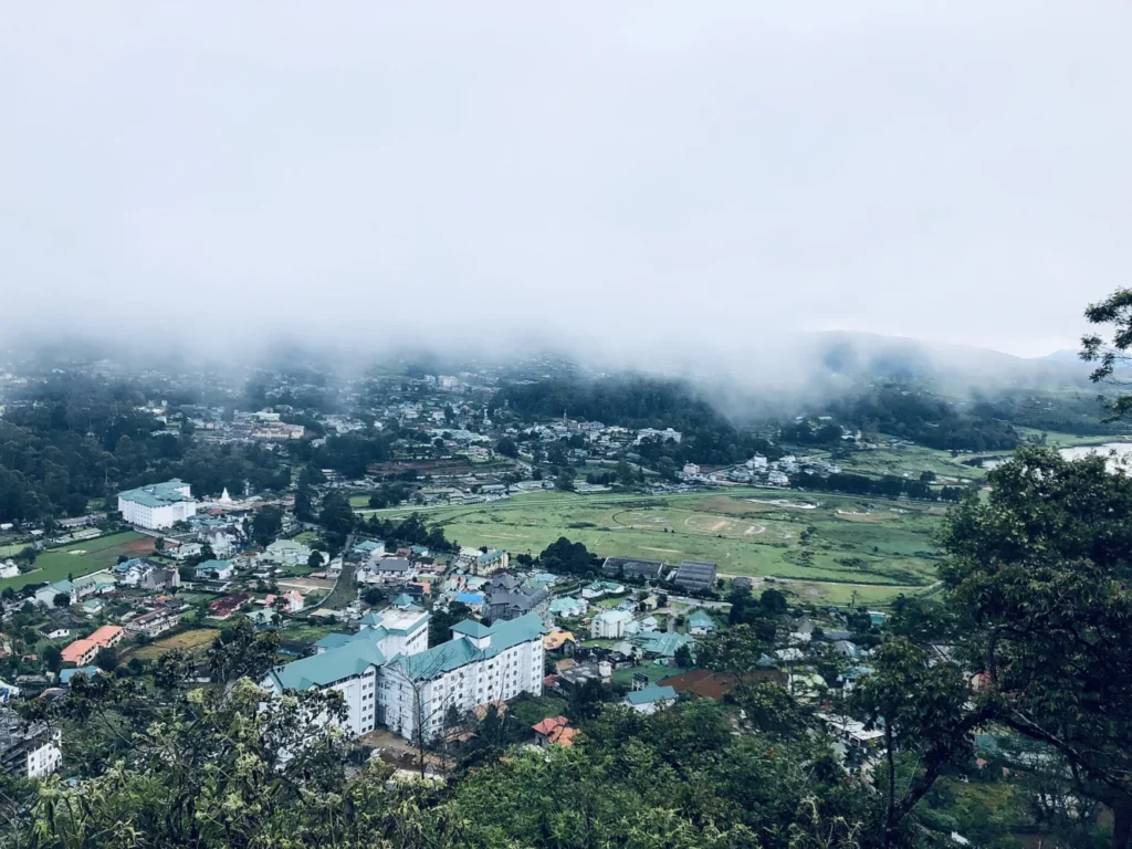 Nuwara Eliya town and green hillside fields beneath low cloud and mist, Sri Lanka