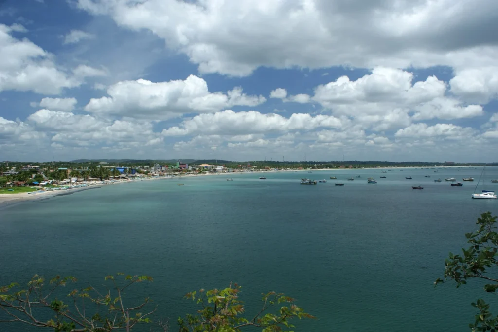 Wide view across blue Trincomalee Bay toward the shoreline beneath large clouds, Sri Lanka